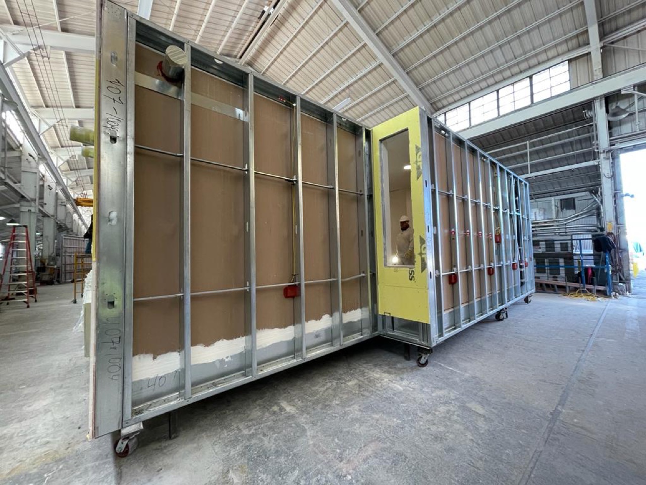 A volumetric module with yellow exterior sheathing and framed window and door openings