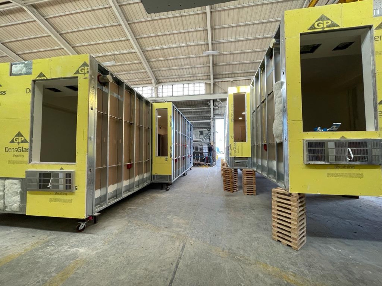 Multiple finished volumetric modules staged in a row on the factory floor